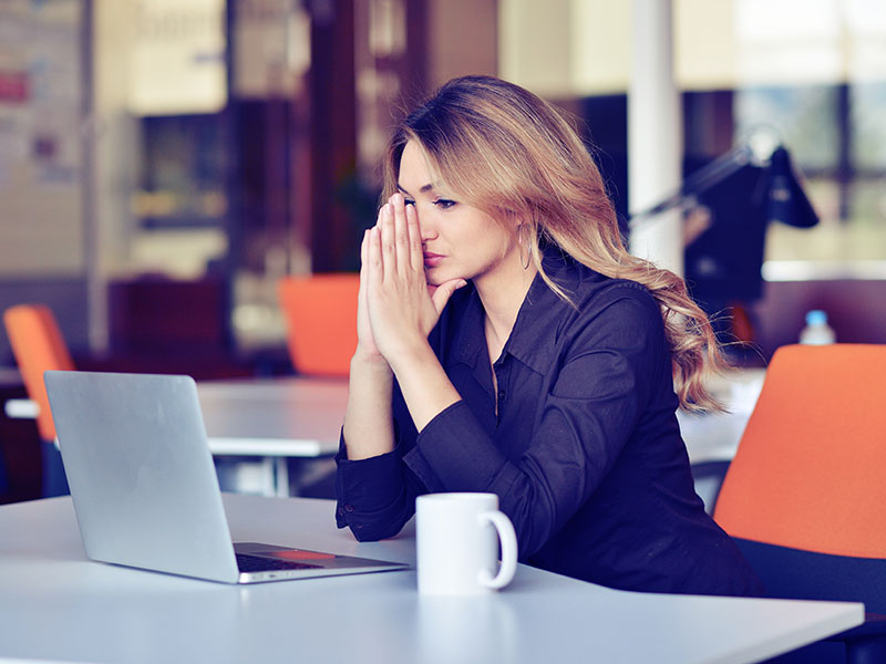 Woman using laptop and looking stressed