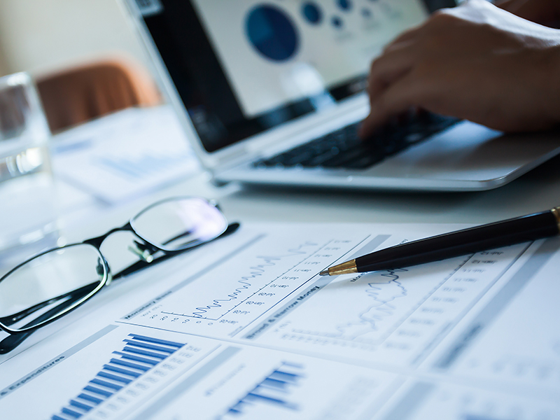 Businessman checking reported profits on the paper and laptop.