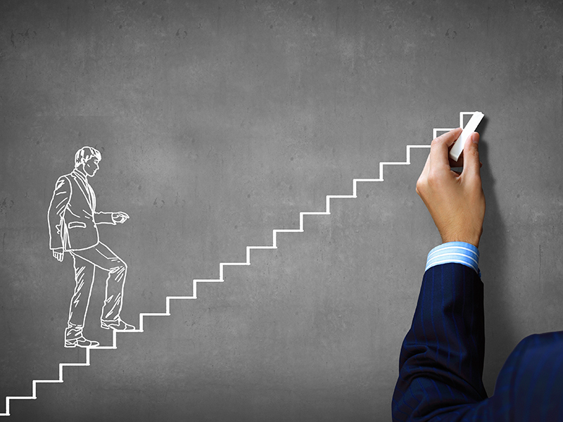 Close up of human hand drawing career ladder with chalk