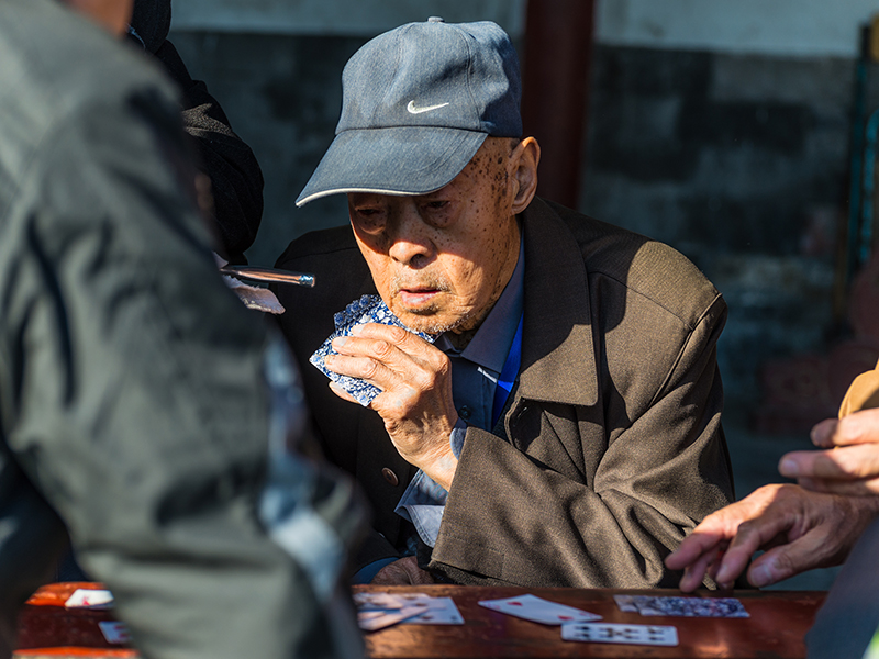 Beijing, China - October 15, 2013: Portrait of a Elderly Chinese men enjoying a game of cards with friends in the surroundings of the Temple of Heaven in Beijing, China.