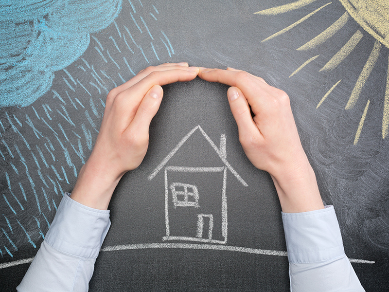 A young businesswoman protects a house from the elements - rain or storm and sun. Blackboard drawing, top view.