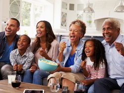 Multi generation black family watching sport on TV at home