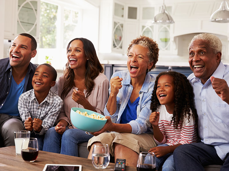 Multi generation black family watching sport on TV at home