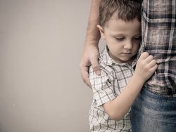 sad son hugging his dad near wall at the day time