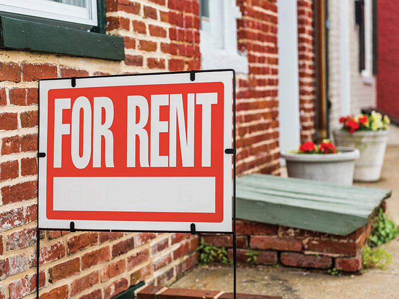 Red For Rent sign closeup against brick building