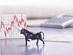 Desk with the figure of a bull and a graph with stock market price