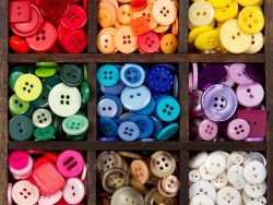 an assortment of buttons in a rainbow of colors, in a printers box