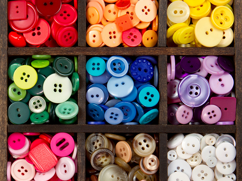 an assortment of buttons in a rainbow of colors, in a printers box