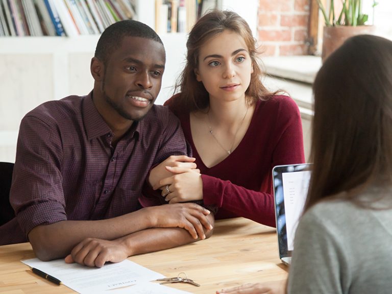 Multiethnic couple considering investment real estate purchase consulting realtor, interracial family listening attentively to mortgage broker thinking of getting bank loan for buying new home house