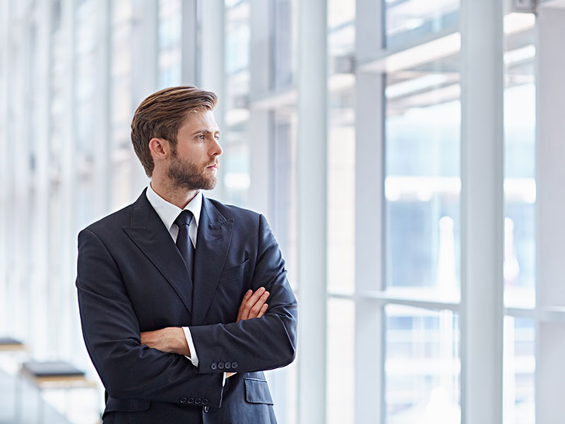 Corporate executive in a modern architectural setting looking confidently out of high rise windows