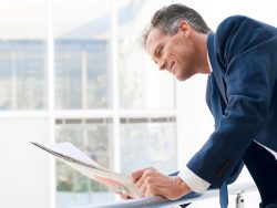 Mature businessman looking and reading newspaper in a modern office