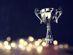 low key image of trophy over wooden table and dark background, with abstract shiny lights