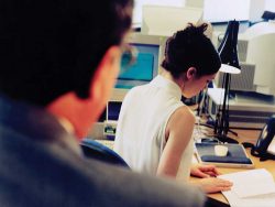 woman working, man over her shoulder