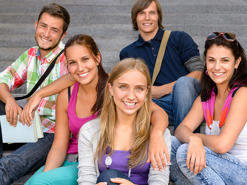 Students sitting on school stairs smiling teens campus college friends