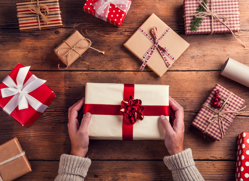 Man holding Christmas presents laid on a wooden table background