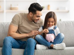 Little girl and dad saving money in piggy bank stock photo