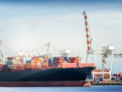 Container Cargo freight ship with ports crane bridge in harbor