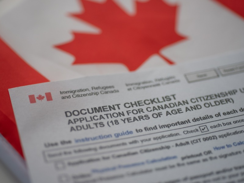 Document check list application for canadian citizenship next to Canadian flag, close up view. stock photo