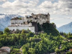 The Hohensalzburg Fortress in Salzburg Austria with Alps rising in the distance. Built over several hundred years (from the 11th to 16th centures), it is one of the largest medieval castles in Europe with a length of 250 m (820 ft) and a width of 150 m (490 ft) and was added to the UNESCO list of world heritage sites 1996. Today it is one of the most recognized landmarks in central Europe